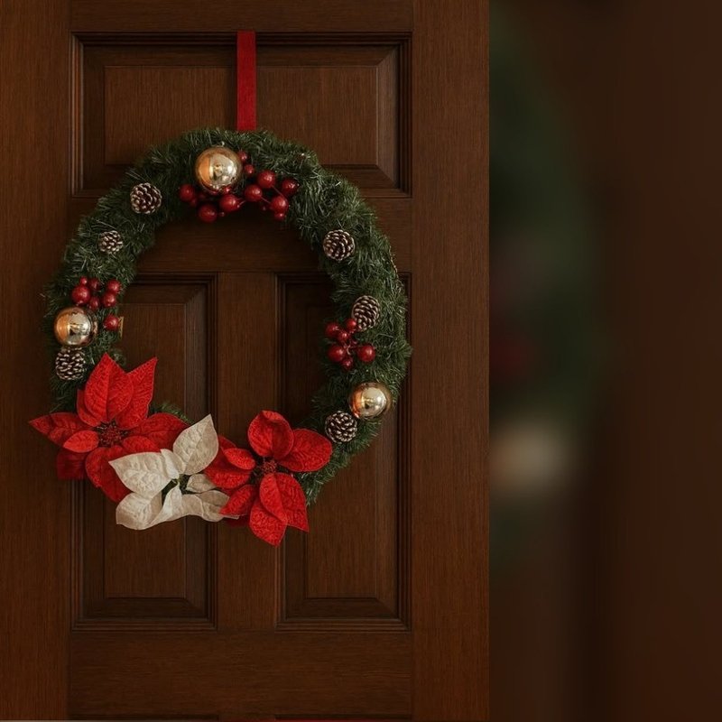 Green garland wreath with pinecones, red berries and red and white poinsettias